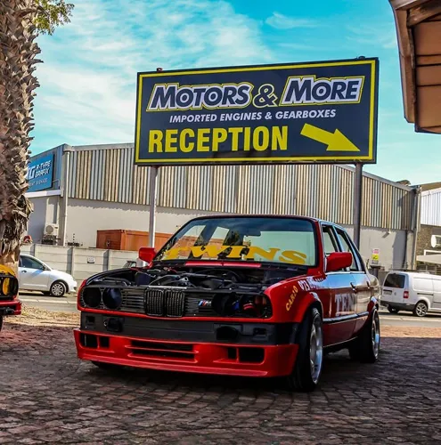 Two staff members standing by the outdoor reception sign at Motors & More Cape Town
