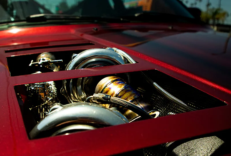 A close up of a red sports car engine bonnet showing the engine