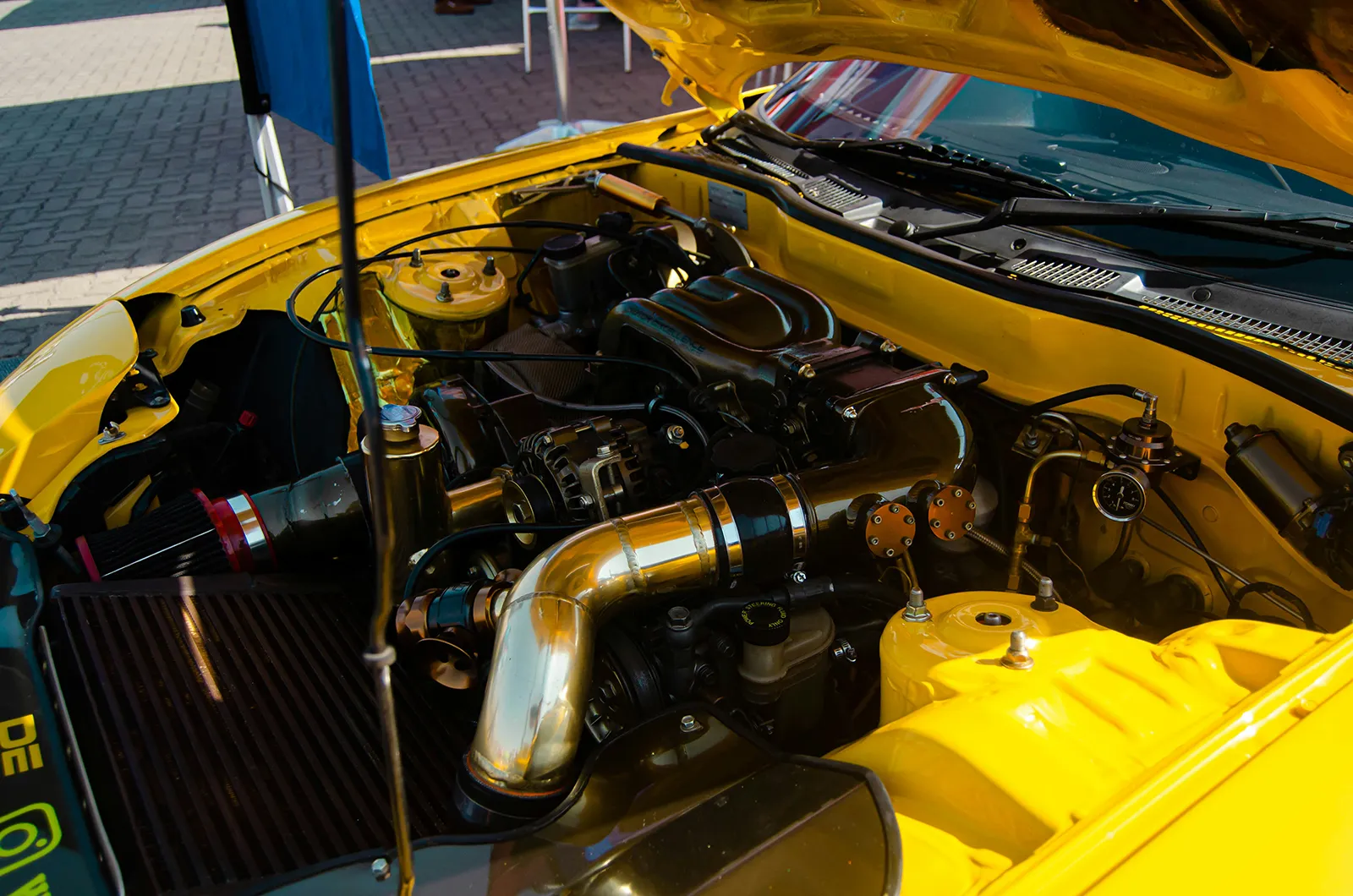 Open engine bay of a yellow car showing engine and parts